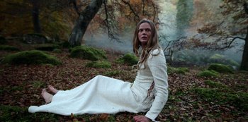 Movie still from “Vikings: Valhalla” (2022), created by Jeb Stuart – A woman sitting on the ground wearing a white dress; Wide shot, Low angle
