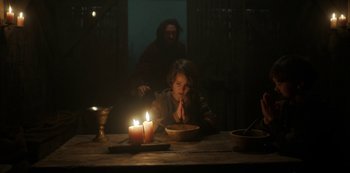 Movie still from “Vikings: Valhalla” (2022), created by Jeb Stuart – A woman sitting at a table with a bowl of food; Medium shot, Low angle