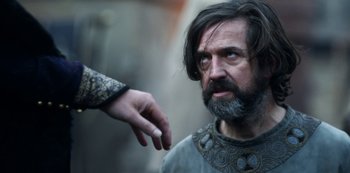 Movie still from “Vikings: Valhalla” (2022), created by Jeb Stuart – A man with long hair and a beard looking at another man's hand; Close Up shot, Low angle