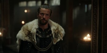 Movie still from “Vikings: Valhalla” (2022), created by Jeb Stuart – A man with a beard wearing a fur coat; Close Up shot, Over the shoulder angle