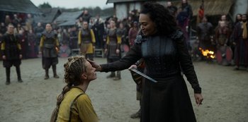 Movie still from “Vikings: Valhalla” (2022), created by Jeb Stuart – A woman in a black dress holding a knife and another woman in a yellow dress; Medium shot, Over the shoulder angle