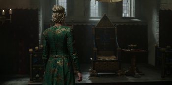 Movie still from “Vikings: Valhalla” (2022), created by Jeb Stuart – A woman in a green dress standing in front of a chair; Medium shot, Over the shoulder angle