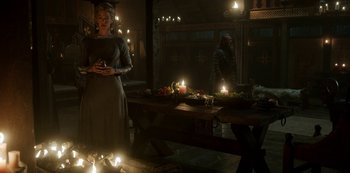Movie still from “Vikings: Valhalla” (2022), created by Jeb Stuart – A woman standing in front of a table with candles on it; Wide shot, Low angle