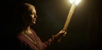 Movie still from “Vikings: Valhalla” (2022), created by Jeb Stuart – A woman holding up a lit candle in the dark; Close Up shot, Low angle