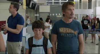 Movie still from “Before Midnight” (2013), directed by Richard Linklater – A man and a boy are walking in an airport; Medium shot, Over the shoulder angle