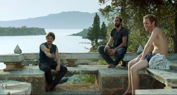 Movie still from “Before Midnight” (2013), directed by Richard Linklater – Two men sitting on a bench near a body of water; Wide shot, Over the shoulder angle