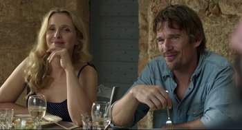 Movie still from “Before Midnight” (2013), directed by Richard Linklater – A man and a woman sitting in front of a dinner table; Medium shot, Over the shoulder angle