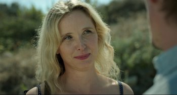 Movie still from “Before Midnight” (2013), directed by Richard Linklater – A beautiful blond haired woman with blue eyes looking at the camera; Close Up shot, Low angle