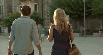 Movie still from “Before Midnight” (2013), directed by Richard Linklater – Two people walking on the sidewalk near a stone building; Medium shot, Over the shoulder angle