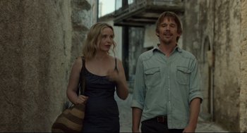 Movie still from “Before Midnight” (2013), directed by Richard Linklater – A man and a woman standing next to each other on a street; Medium shot, Over the shoulder angle