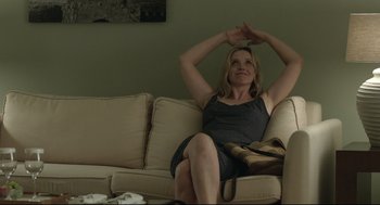 Movie still from “Before Midnight” (2013), directed by Richard Linklater – A woman sitting on a couch in a living room; Medium shot, Over the shoulder angle