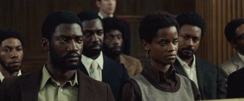 Movie still from “Small Axe” (2020), directed by Steve McQueen – A group of people standing next to each other in a courtroom; Medium shot, Over the shoulder angle