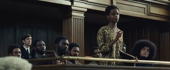 Movie still from “Small Axe” (2020), directed by Steve McQueen – A woman standing in front of a group of people; Medium shot, Low angle