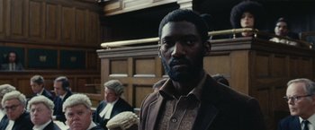 Movie still from “Small Axe” (2020), directed by Steve McQueen – A man standing in front of a judge in a courtroom; Close Up shot, High angle