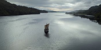 Movie still from “Vikings: Valhalla” (2022), created by Jeb Stuart – A boat floating on a body of water near trees; Extreme Wide shot, High angle