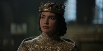 Movie still from “Vikings: Valhalla” (2022), created by Jeb Stuart – A woman wearing a gold crown in a dark room; Close Up shot, Over the shoulder angle