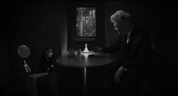 Movie still from “What Did Jack Do?” (2017), directed by David Lynch – A man sitting at a table in front of another man; Medium shot, Over the shoulder angle