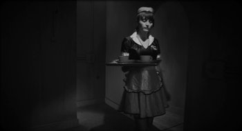 Movie still from “What Did Jack Do?” (2017), directed by David Lynch – A woman holding a tray while standing in a room; Medium shot, High angle
