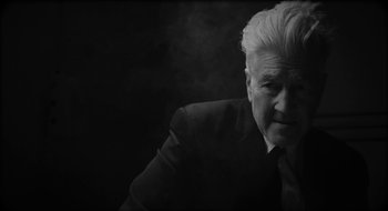 Movie still from “What Did Jack Do?” (2017), directed by David Lynch – An older man in a black suit and white shirt; Close Up shot, Low angle