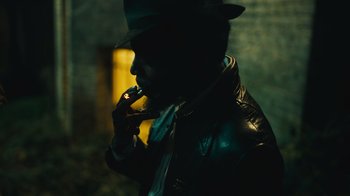 Movie still from “Small Axe” (2020), directed by Steve McQueen – A man wearing a hat is smoking a cigarette in the dark; Extreme Close Up shot, Low angle