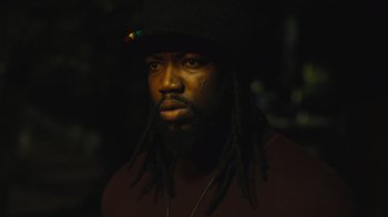 Movie still from “Small Axe” (2020), directed by Steve McQueen – A person with dreadlocks wearing a hat; Close Up shot, Low angle