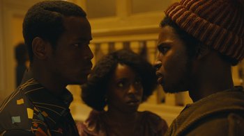 Movie still from “Small Axe” (2020), directed by Steve McQueen – Two men and a woman are standing in a room; Close Up shot, Over the shoulder angle