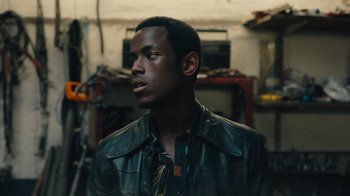 Movie still from “Small Axe” (2020), directed by Steve McQueen – A man in a leather jacket looking to his left; Close Up shot, Low angle