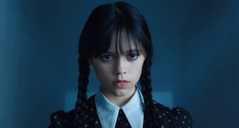 Movie still from “Wednesday” (2022), created by Miles Millar – A young woman with long black plaited pigtails; Close Up shot, Low angle