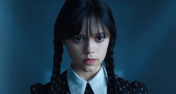 Movie still from “Wednesday” (2022), created by Miles Millar – A young woman with long black plaited pigtails; Close Up shot, Low angle