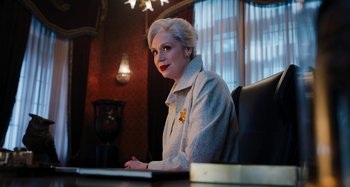 Movie still from “Wednesday” (2022), created by Miles Millar – A woman sitting at a desk in front of a computer; Medium shot, Low angle