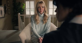 Movie still from “Wednesday” (2022), created by Miles Millar – A woman sitting on a chair in front of a man; Medium shot, Over the shoulder angle