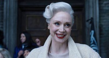 Movie still from “Wednesday” (2022), created by Miles Millar – An older woman with white hair smiling for the camera; Close Up shot, Low angle