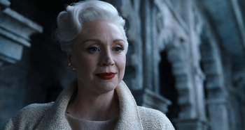 Movie still from “Wednesday” (2022), created by Miles Millar – An older woman with white hair wearing a white coat; Close Up shot, Low angle