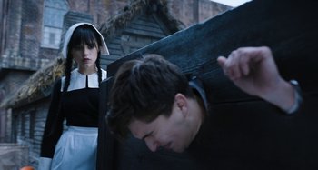 Movie still from “Wednesday” (2022), created by Miles Millar – A woman in a maid's uniform looking at a man in a prison uniform; Medium shot, Over the shoulder angle