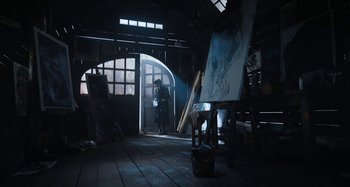 Movie still from “Wednesday” (2022), created by Miles Millar – A person standing in front of an easel in a room; Wide shot, Low angle