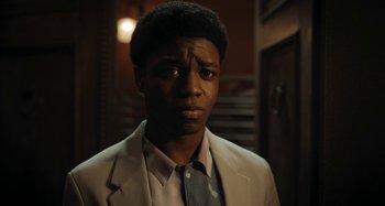 Movie still from “Wednesday” (2022), created by Miles Millar – A man in a suit and tie looking at the camera; Close Up shot, Low angle