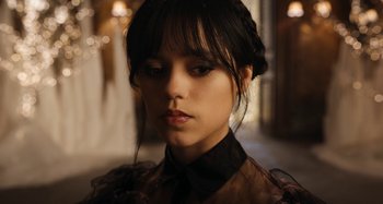 Movie still from “Wednesday” (2022), created by Miles Millar – A person wearing a dress; Close Up shot, Low angle