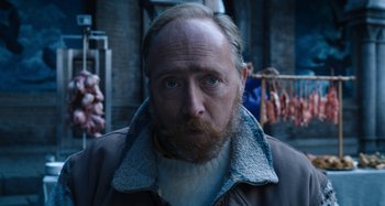 Movie still from “Wednesday” (2022), created by Miles Millar – A person with a beard wearing a jacket; Close Up shot, Low angle