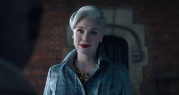 Movie still from “Wednesday” (2022), created by Miles Millar – A woman with white blonde hair and blue eyes; Close Up shot, Low angle