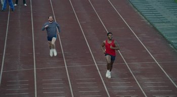 Movie still from “Small Axe” (2020), directed by Steve McQueen – Two men are running on a race track; Wide shot, High angle
