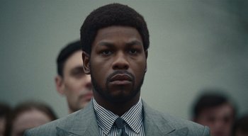 Movie still from “Small Axe” (2020), directed by Steve McQueen – A man wearing a suit and tie in front of another man in a suit; Close Up shot, Low angle