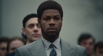 Movie still from “Small Axe” (2020), directed by Steve McQueen – A man in a suit and tie standing in front of another man; Close Up shot, Low angle