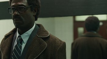 Movie still from “Small Axe” (2020), directed by Steve McQueen – A person wearing a suit and tie; Close Up shot, Over the shoulder angle