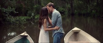 A man and a woman kissing in front of a body of water