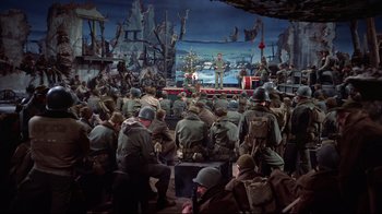 Movie still from “White Christmas” (1954), directed by Michael Curtiz – A group of men in military uniforms sitting in front of an audience; Wide shot, High angle