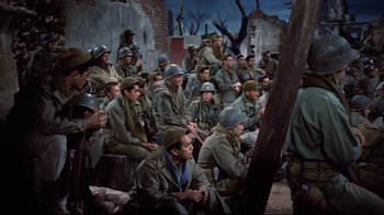 Movie still from “White Christmas” (1954), directed by Michael Curtiz – A large group of men sitting on the ground; Wide shot, High angle