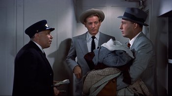 Movie still from “White Christmas” (1954), directed by Michael Curtiz – A group of men standing next to each other in a room; Medium shot, Over the shoulder angle