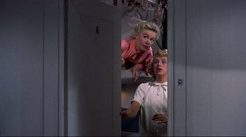 Movie still from “White Christmas” (1954), directed by Michael Curtiz – A couple of women standing next to each other in front of a door; Medium shot, Low angle