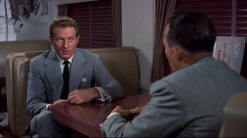 Movie still from “White Christmas” (1954), directed by Michael Curtiz – A man in a suit and tie sitting in front of another man in a suit and tie; Medium shot, Over the shoulder angle