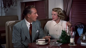 Movie still from “White Christmas” (1954), directed by Michael Curtiz – A man and a woman sitting at a table; Medium shot, Low angle